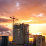 High-rise building under construction with a tower crane at sunset, representing the impact of strong leadership on construction quality and project success.