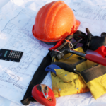 Construction blueprints laid out with a hard hat, tools, and calculator, representing the planning and coordination required for successful building projects.